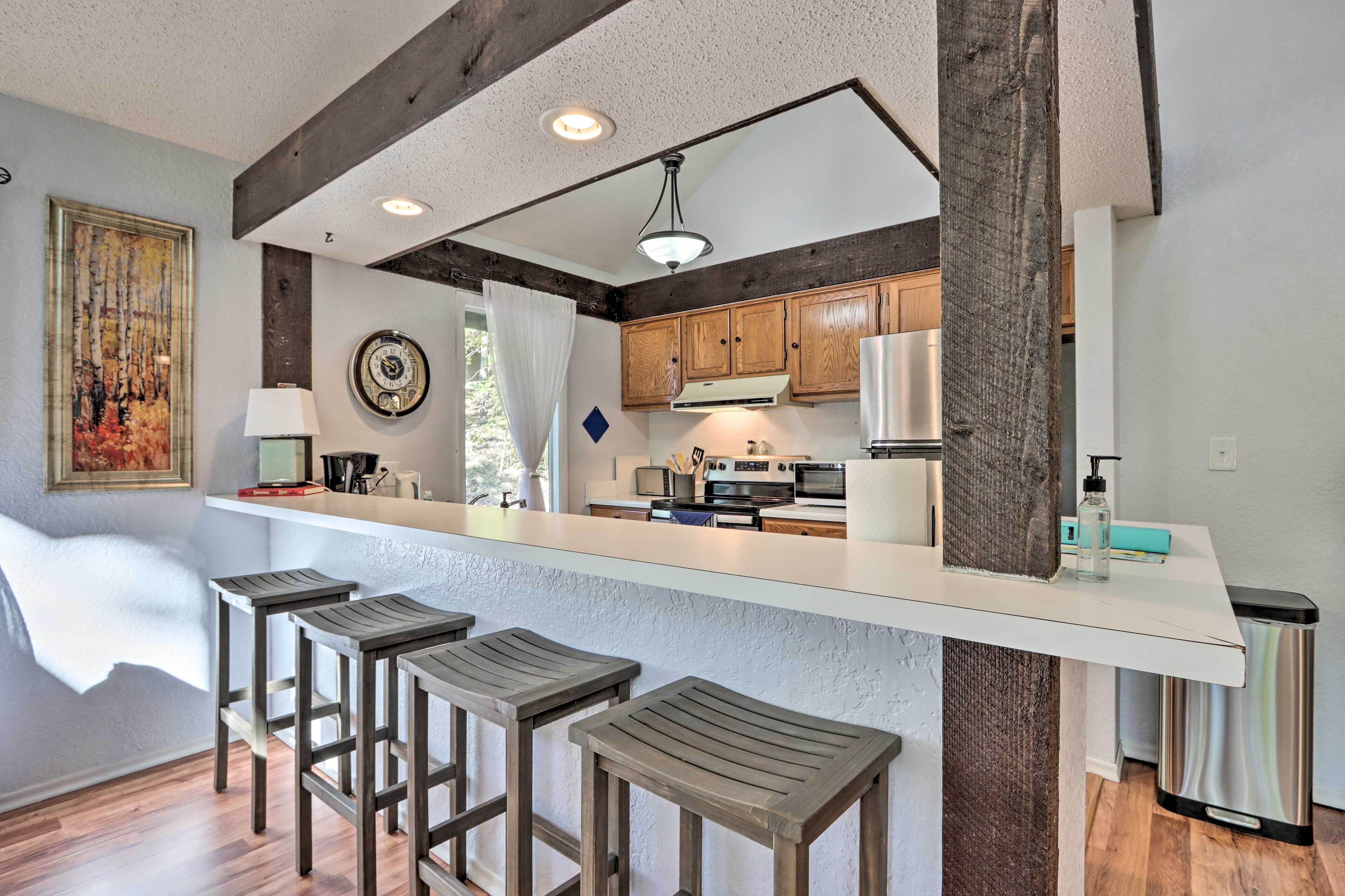 A modern kitchen with wooden bar stools, a white countertop, and built-in appliances.