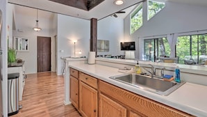 Una cocina moderna con armarios de madera, un lavamanos de acero inoxidable y un amplio ventanal que proporciona luz natural.