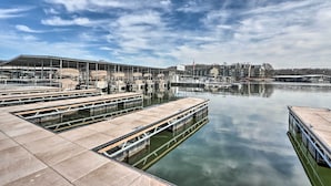 Un puerto deportivo con barcos amarrados, un edificio grande con un letrero y una masa de agua tranquila.