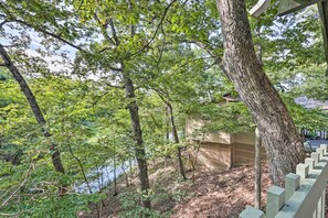 A wooded area with a wooden deck and a building with a lattice facade. - Pools, Water Park! Margaritaville Resort Home (Osage Beach)