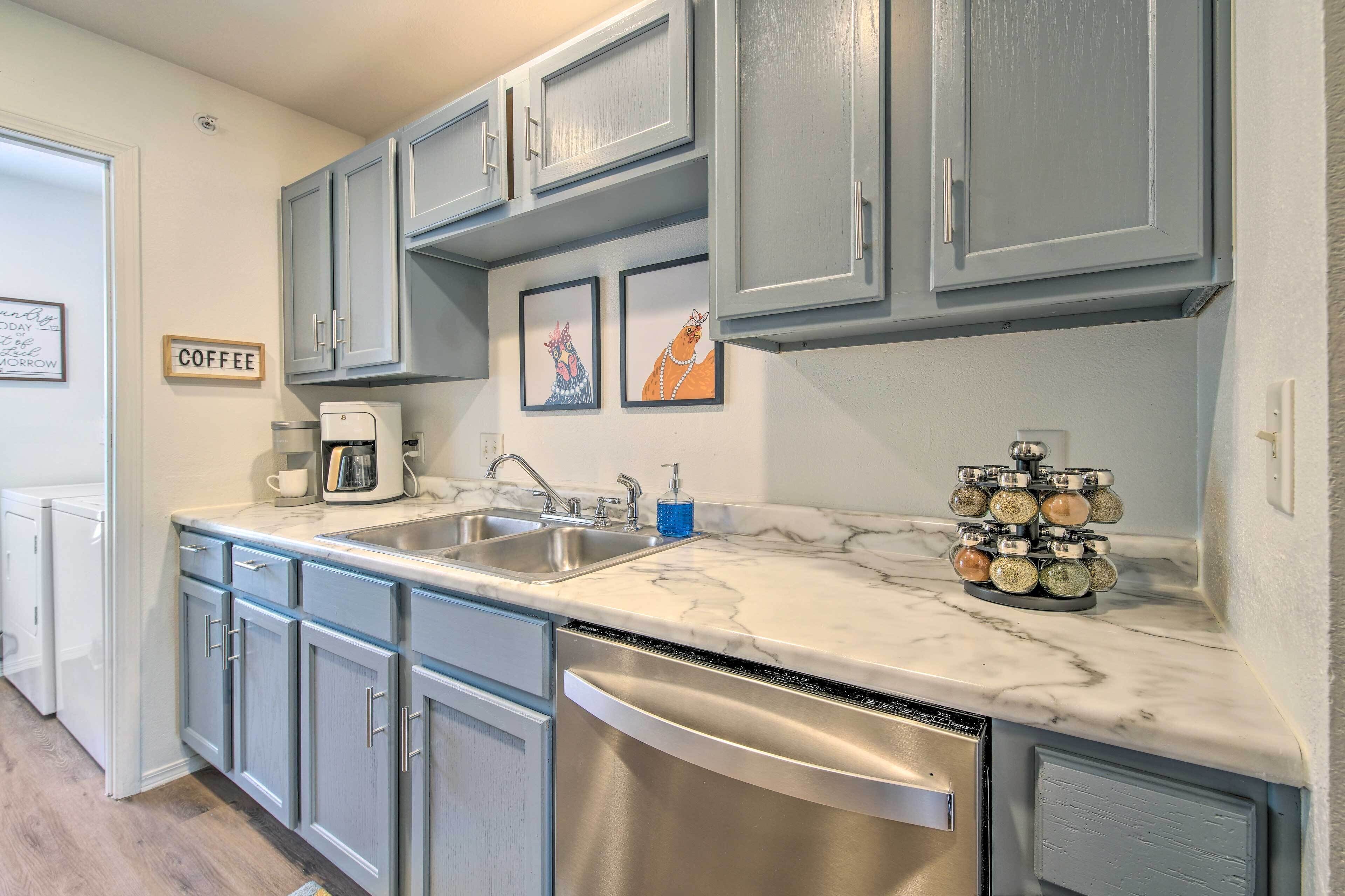 A kitchen with grey cabinets, a coffee maker, a sink, and a spice rack.