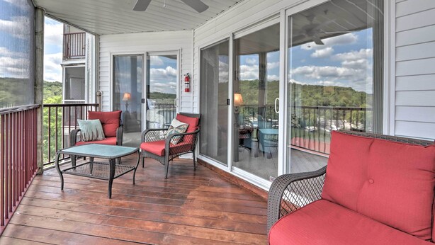 A covered porch with a ceiling fan, a table, and two wicker chairs with cushions. - 'the Lake Escape w/ Balcony & Pool Access! (Camdenton)