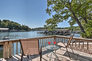 Una terraza de madera con dos sillas y una mesa, con vistas a una marina con muelles y barcos.