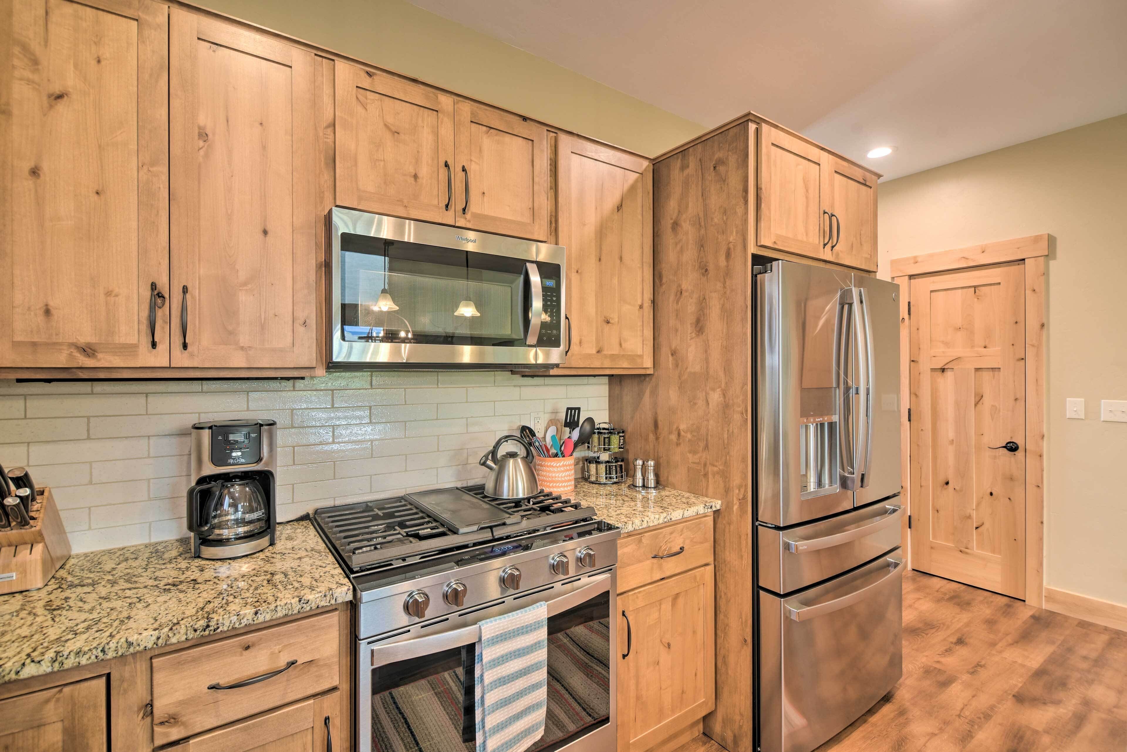 A kitchen with wooden cabinets, a stainless steel microwave, a refrigerator, a stove, and a coffee maker.