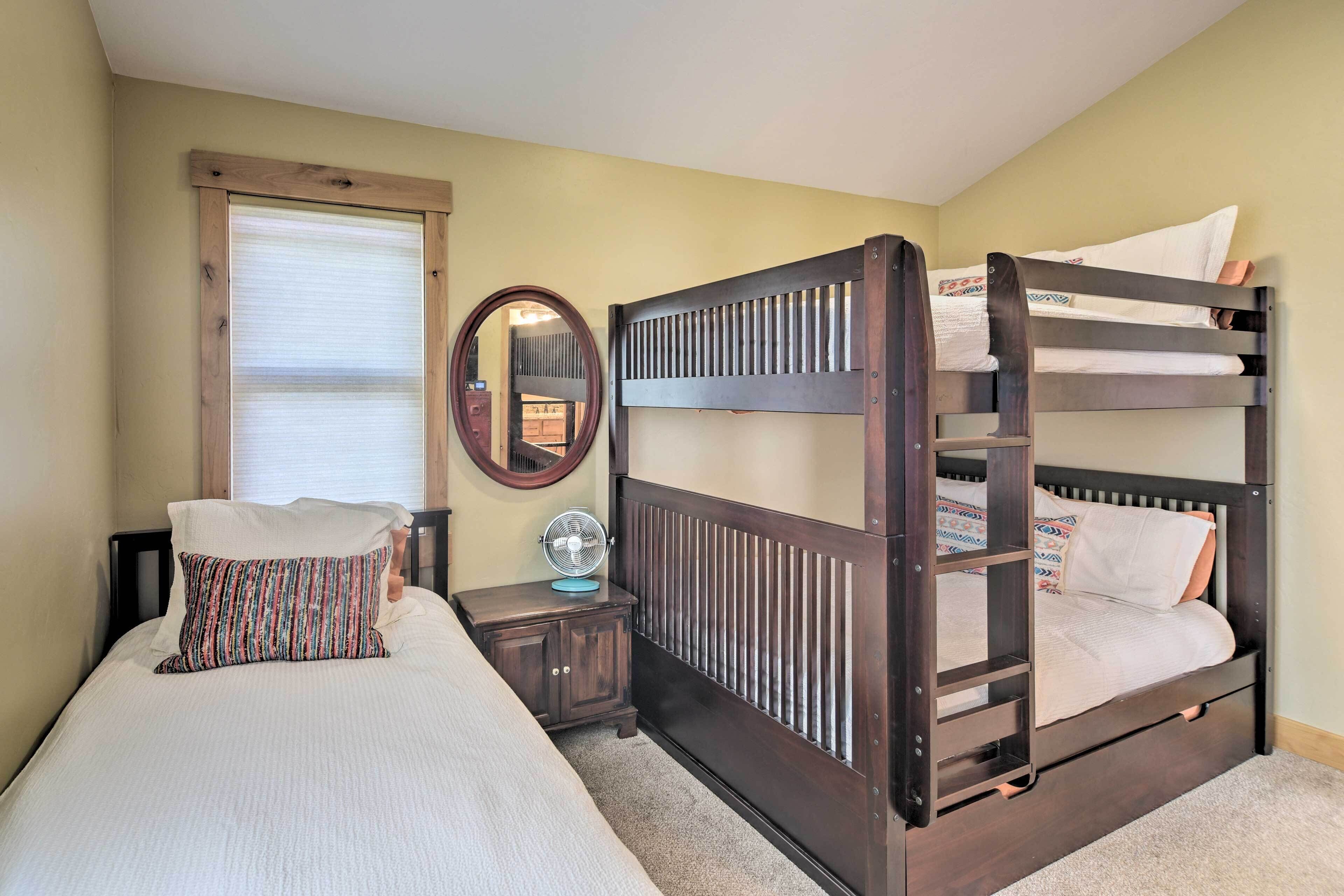 A bedroom with a bunk bed, a bedside table with a lamp, and a window with blinds.