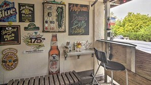 A bar area with various beer bottles and memorabilia on the wall, a wooden bench, and a black chair. - Harpers Ferry Apartment w/ Private Pool & Hot Tub! (Harpers Ferry)
