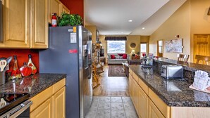 A kitchen with granite countertops, wooden cabinets, a refrigerator, and a dining area with a table and chairs. - 11 Mi to Keystone: Silverthorne Condo w/ Deck (Silverthorne)