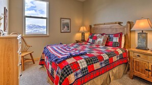 A bedroom with a large bed, a wooden dresser, a chair, a window with a mountain view, and a framed picture on the wall. - 11 Mi to Keystone: Silverthorne Condo w/ Deck (Silverthorne)
