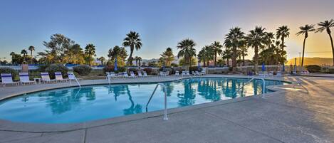 A swimming pool with lounge chairs and palm trees.