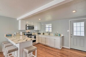 A kitchen with white cabinets, a marble countertop, and a wooden floor. - 4 Blocks to Ocean: Water-view Surfside Beach Home! (Freeport)