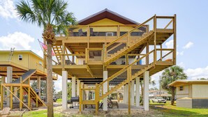 A multi-story wooden structure with a balcony, a staircase, and a flag. - 'sunny Side Up' Canal-front Getaway w/ Dock! (Suwannee)