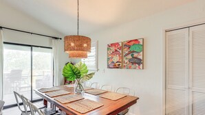 A dining area with a wooden table, white chairs, woven placemats, a hanging light fixture, and a large green plant. - 'sunny Side Up' Canal-front Getaway w/ Dock! (Suwannee)