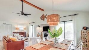A modern living room with a wooden dining table, white chairs, a brown sofa, and a ceiling fan. - 'sunny Side Up' Canal-front Getaway w/ Dock! (Suwannee)