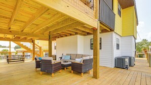 A covered outdoor deck with wicker furniture and a view of a white building. - 'sunny Side Up' Canal-front Getaway w/ Dock! (Suwannee)