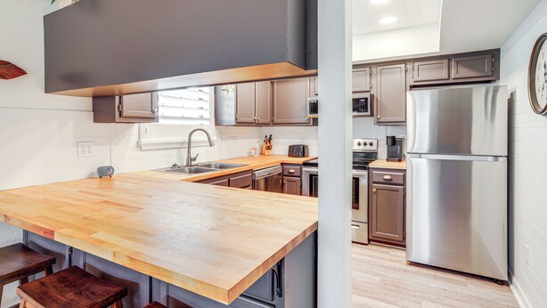 A modern kitchen with wooden countertops, stainless steel appliances, and a built-in oven. - 'sunny Side Up' Canal-front Getaway w/ Dock! (Suwannee)