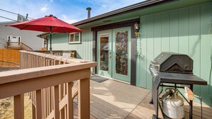 A deck with a red umbrella, a barbecue grill, and a propane tank. - Near Red Rocks, Hiking & Skiing: Kittredge Condo! (Kittredge)