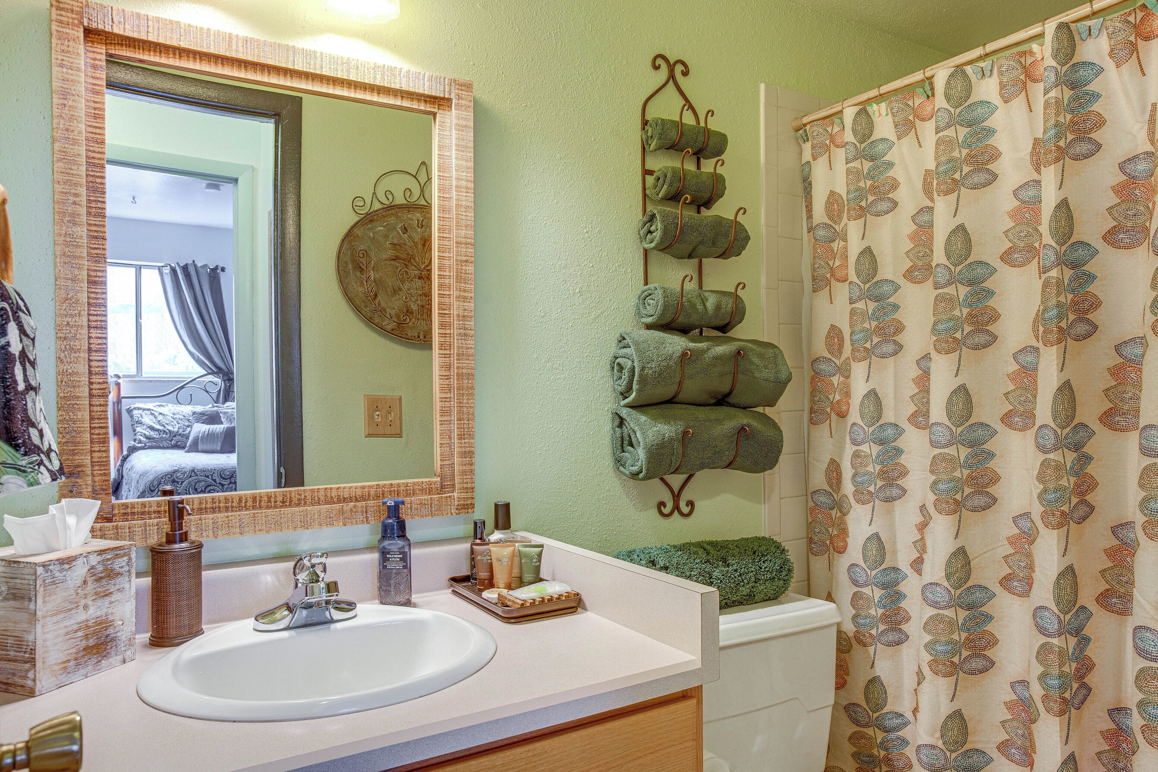 A bathroom with a sink, mirror, towel rack, and shower curtain.