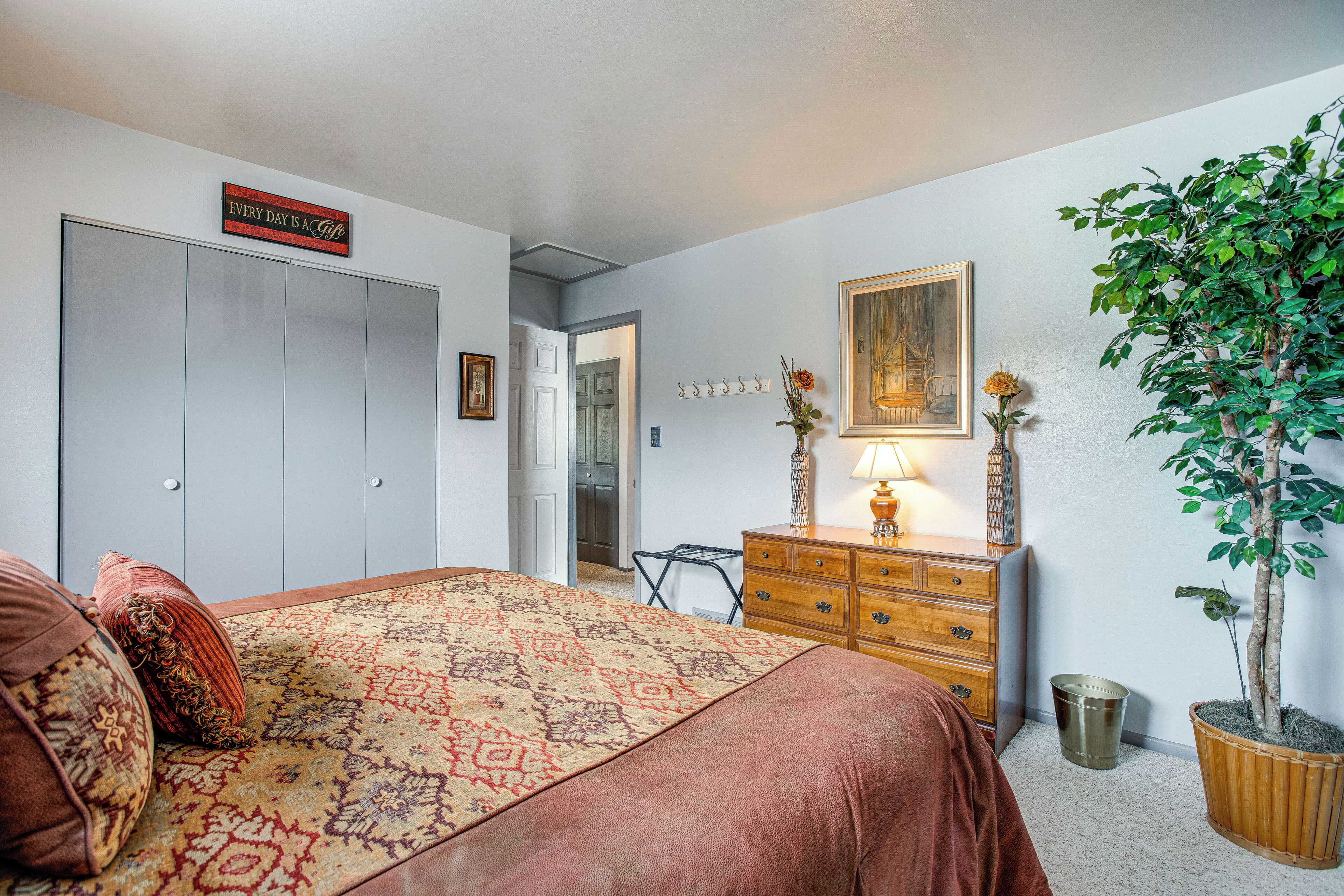 Une chambre à coucher avec un lit, une commode et une plante en pot.