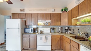 A kitchen with wooden cabinets, a white refrigerator, a stove, and a microwave. - Near Red Rocks, Hiking & Skiing: Kittredge Condo! (Kittredge)
