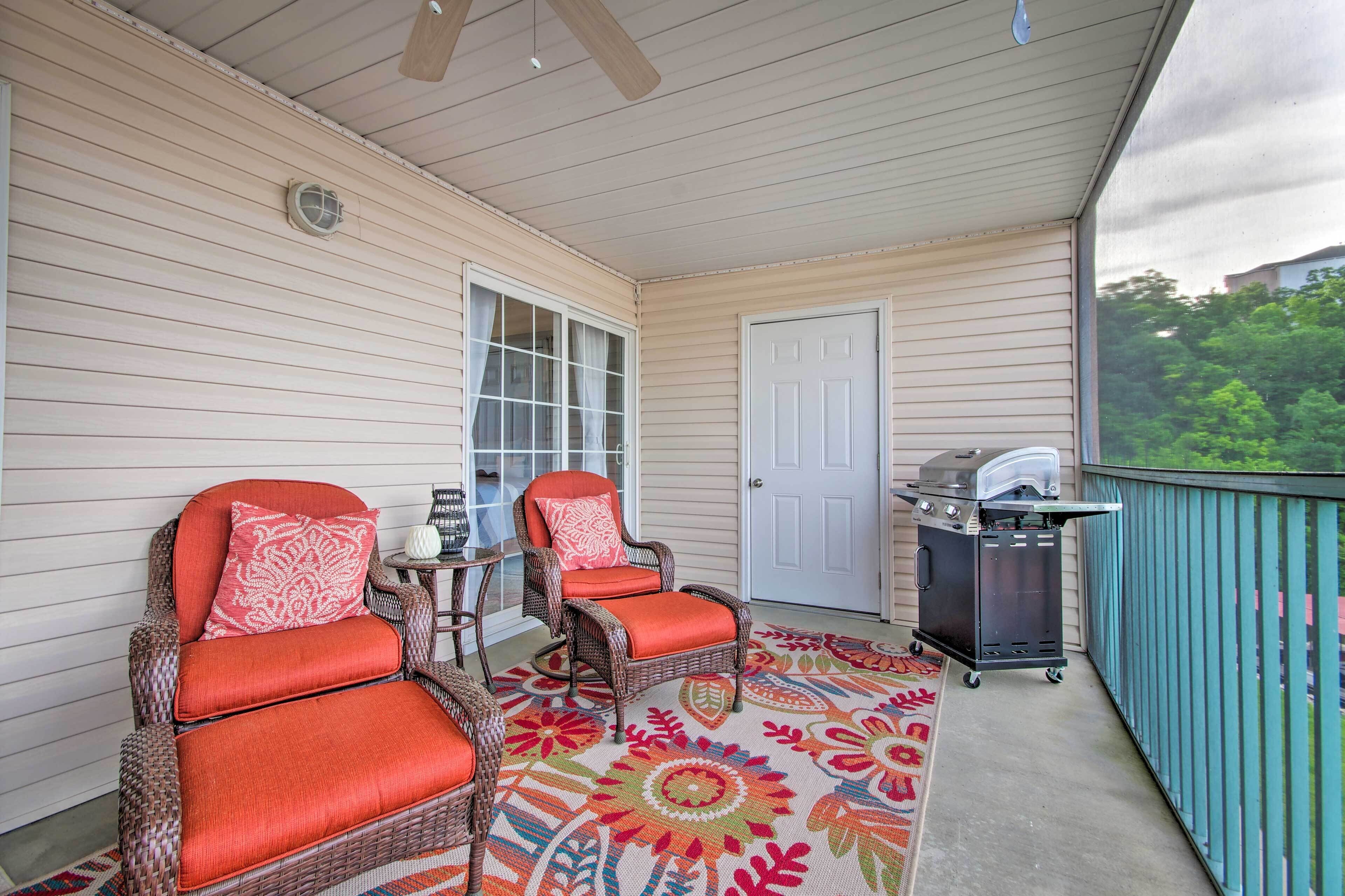 A covered porch with wicker chairs, a grill, and a patterned rug.