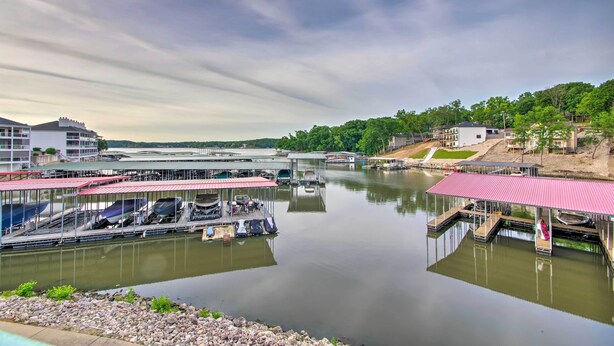 A marina with docked boats, a covered boat house, and a bridge in the background. - Screened Balcony w/ Views: Sleek Lake Ozark Gem! (Lake Ozark)