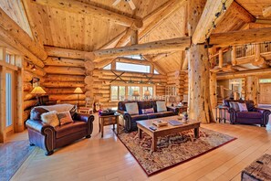 A spacious log cabin interior with a high ceiling, multiple seating areas, and large windows allowing natural light. - 22str-00019 Fairplay High Country Lodge w/ Hot Tub (Fairplay)