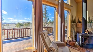 Una habitación acogedora con un ventanal grande, un sillón cómodo, chimenea y una terraza exterior.