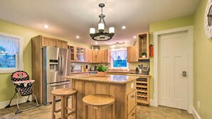 Una cocina con armarios de madera, un refrigerador de acero inoxidable, un taburete de bar y una ventana con vistas.
