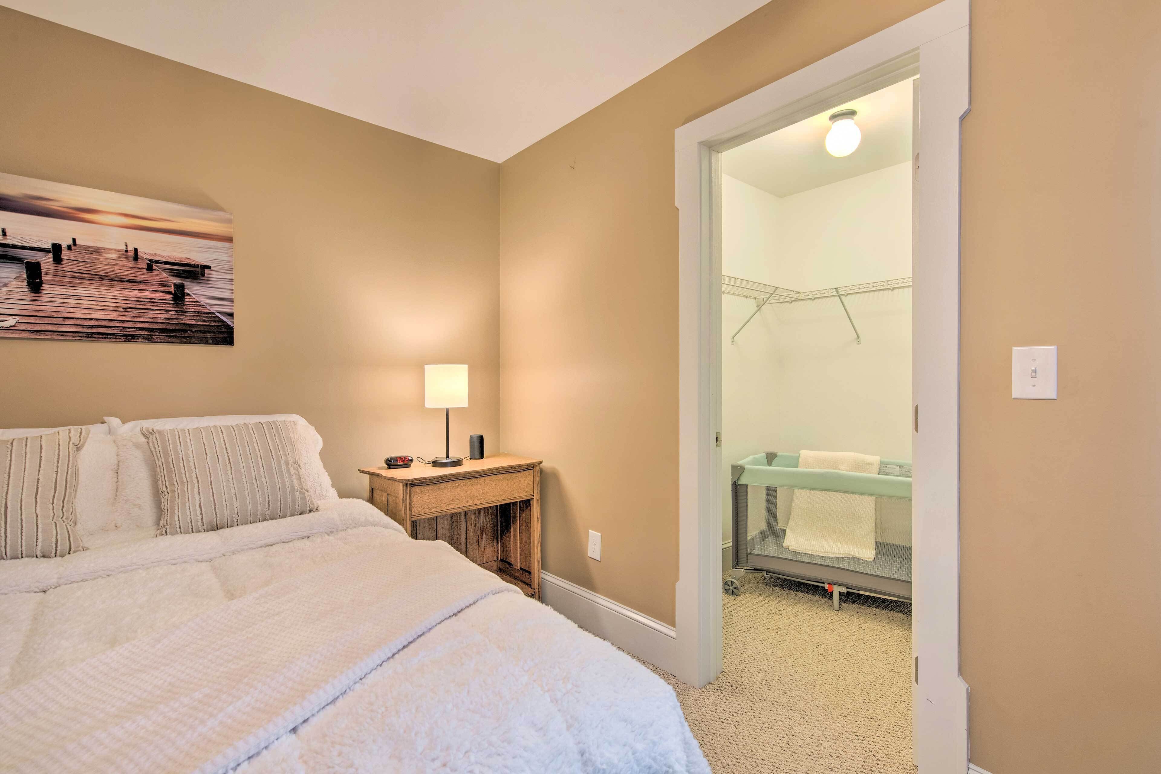 A hotel room with a bed, a nightstand, a lamp, and a bathroom visible through an open door.