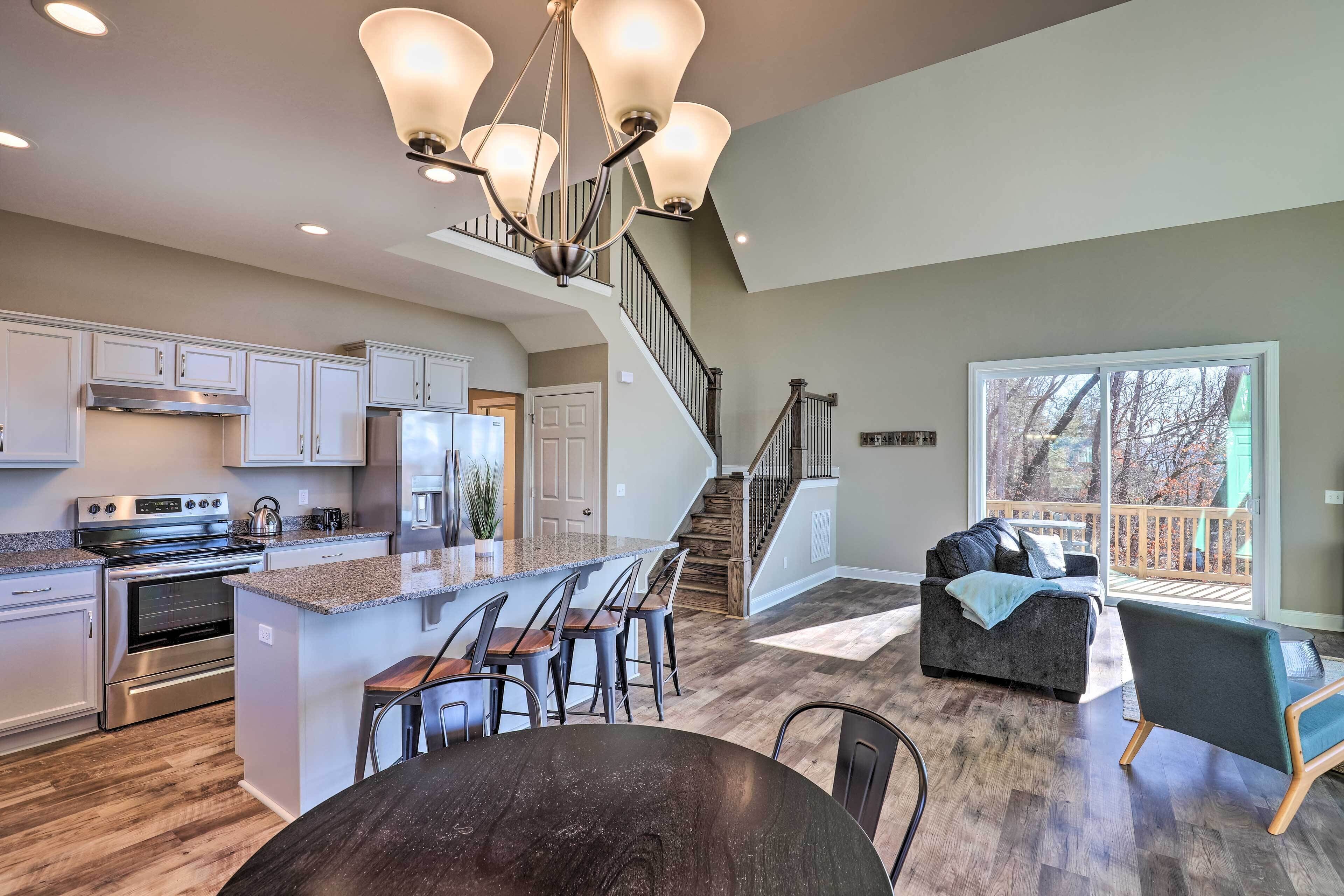A modern kitchen with a central island, stainless steel appliances, and a staircase leading to a balcony.