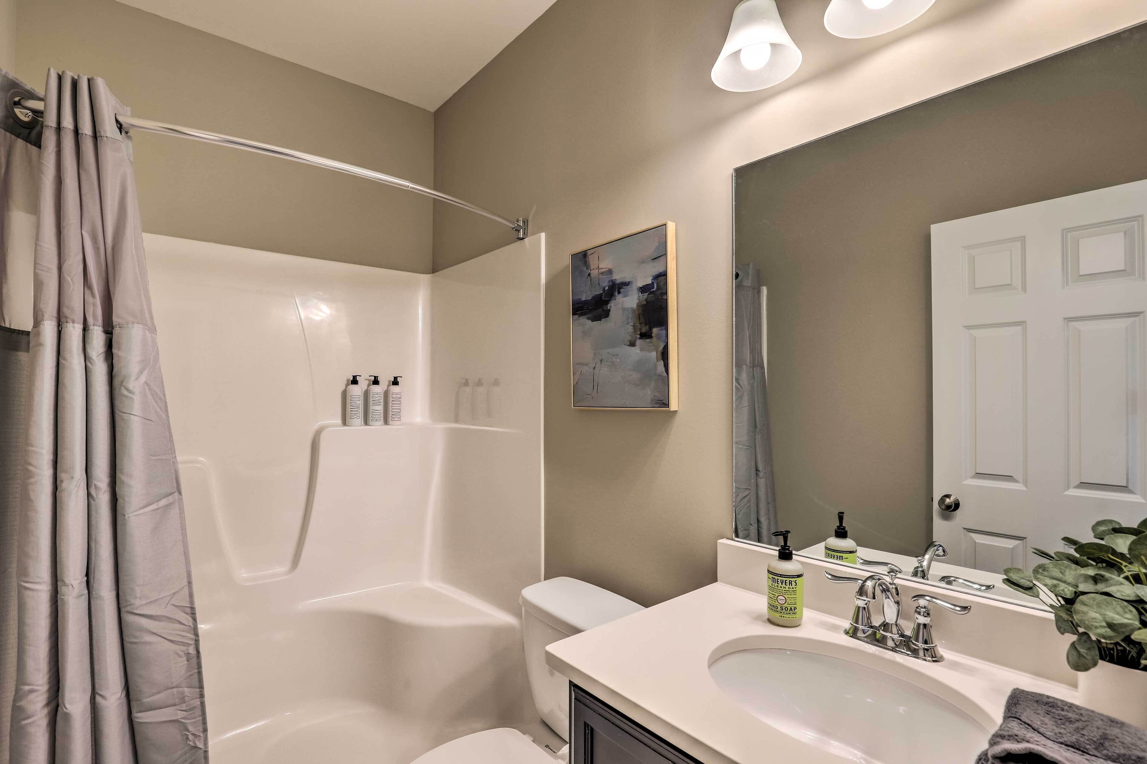 Een moderne badkamer met douche, toilet, wastafel en een grote spiegel.