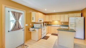 A compact kitchen with wooden cabinets, a microwave, stove, and refrigerator. - Rapid City Cabin w/ Hiking & ATV Trail Access (Rapid City)