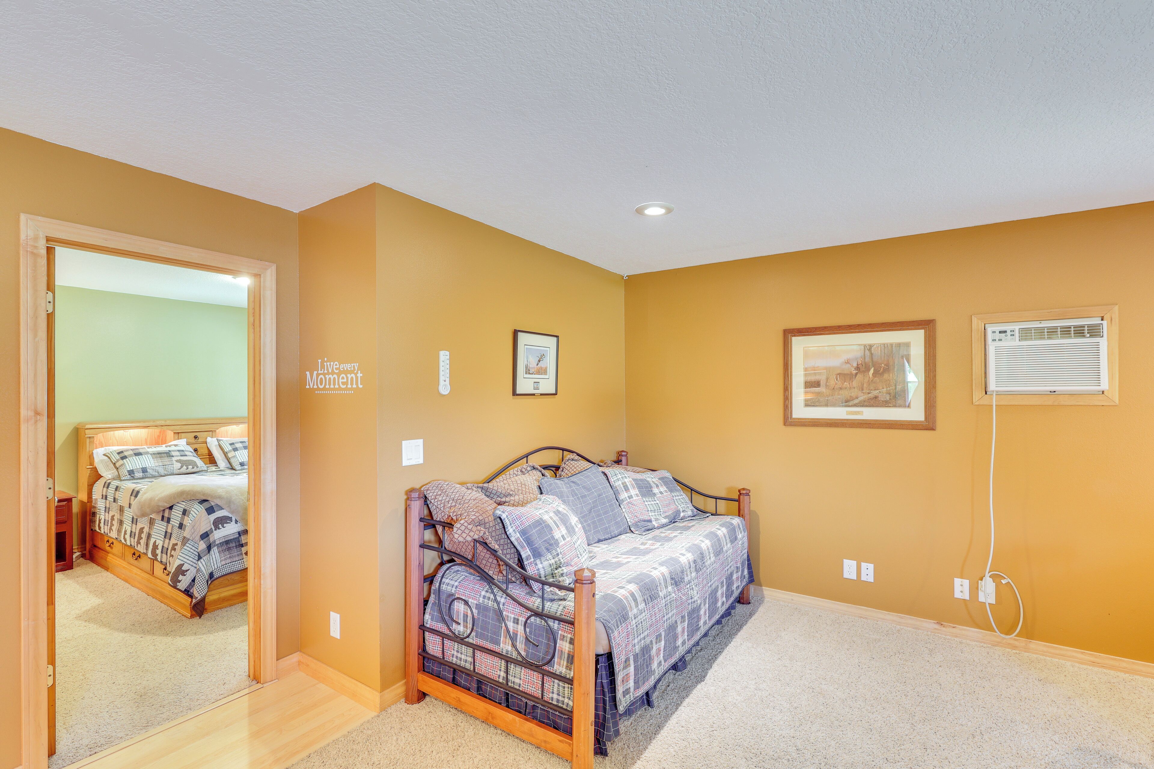A bedroom with a bed, a door, and a wall with two framed pictures.