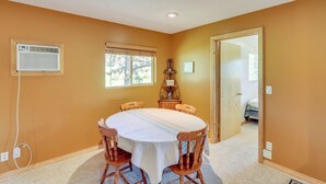 A dining area with a round table, chairs, a window, and an air conditioning unit. - Rapid City Cabin w/ Hiking & ATV Trail Access (Rapid City)