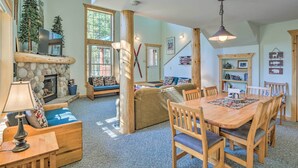 A cozy living room with a stone fireplace, wooden furniture, and a dining area with a table and chairs. - 6 Mi to Turquoise Lake: Retreat w/ Covered Deck! (Leadville)