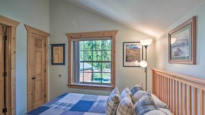 A bedroom with a large bed, wooden headboard, a window with a view of greenery, and a framed picture on the wall. - 6 Mi to Turquoise Lake: Retreat w/ Covered Deck! (Leadville)