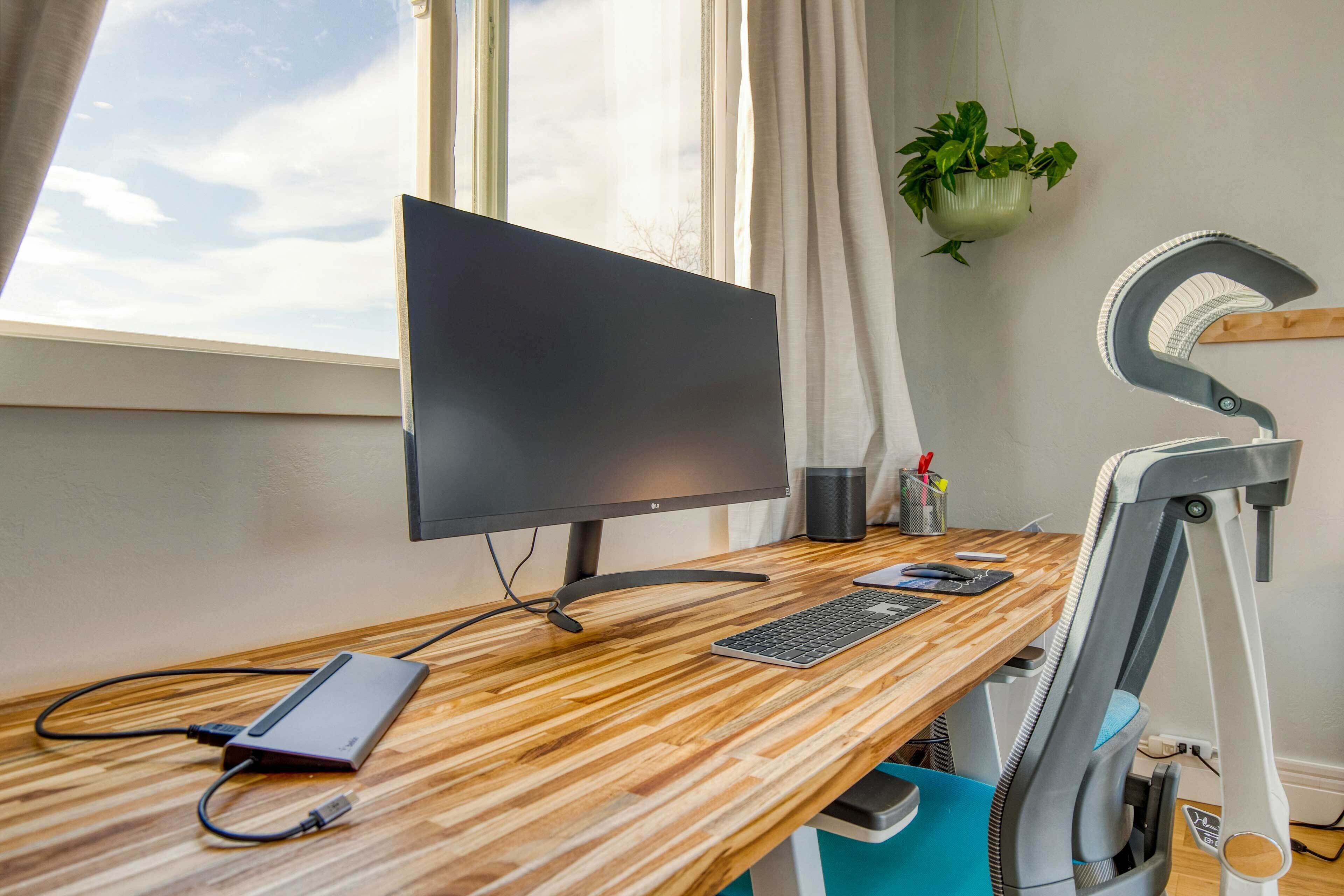A wooden desk with a computer monitor, keyboard, and a power strip.
