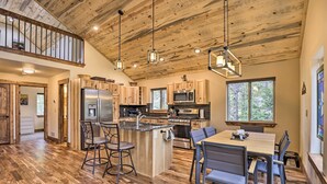 A spacious kitchen with wooden cabinets, a central island, and a dining area with chairs. - Rocky Mountain Alma Cabin With Deck & Hot Tub! (Alma)