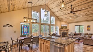 A spacious kitchen with a central island, wooden flooring, and large windows offering views of the outdoors. - Rocky Mountain Alma Cabin With Deck & Hot Tub! (Alma)
