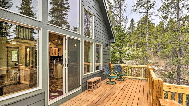 A wooden deck with outdoor seating and a view of a forested area. - Rocky Mountain Alma Cabin With Deck & Hot Tub! (Alma)