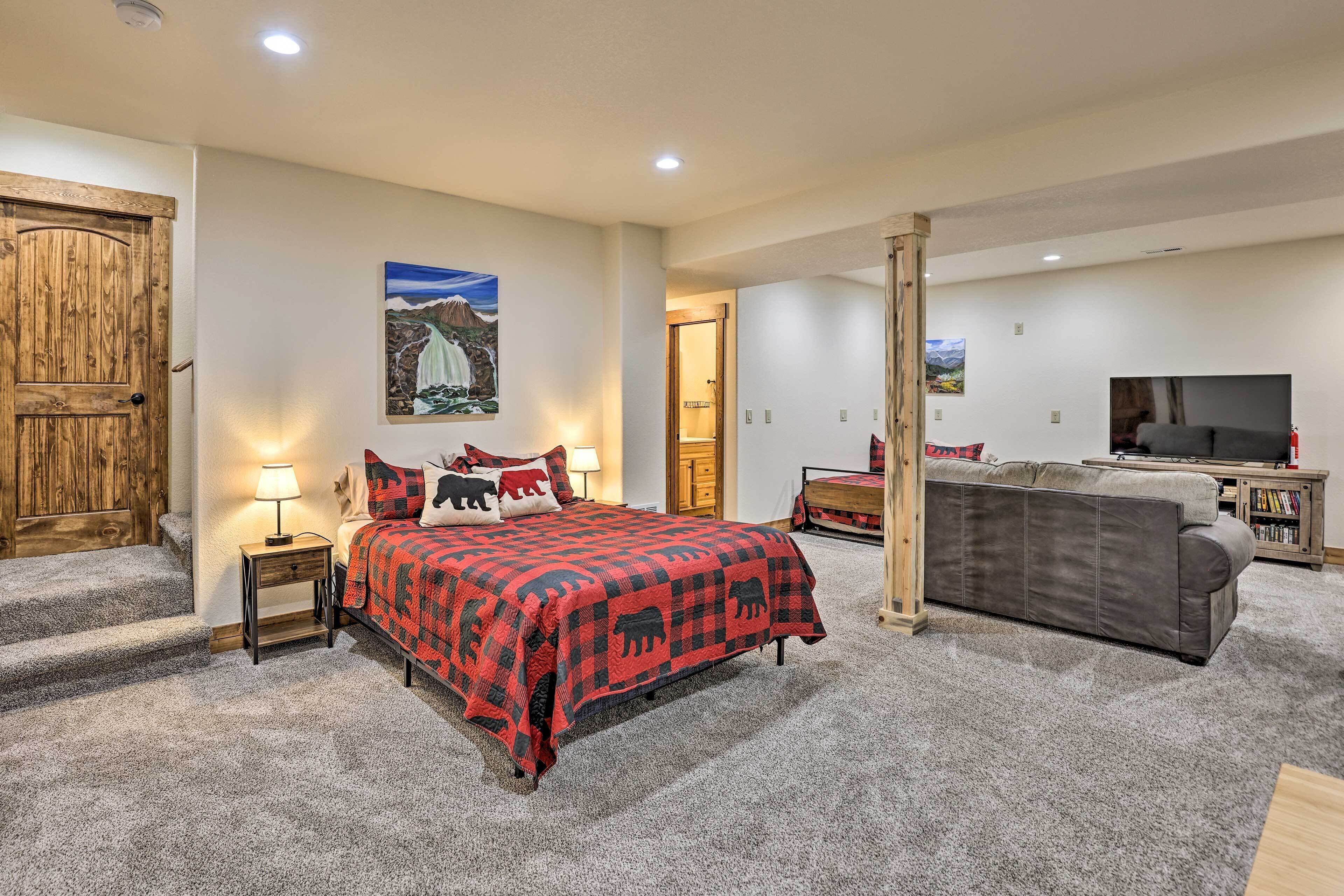 Un dormitorio con una cama, televisor, sofá y puerta de madera.