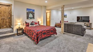 A bedroom with a bed, a TV, a sofa, and a wooden door. - Rocky Mountain Alma Cabin With Deck & Hot Tub! (Alma)