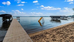 A waterfront dock with a metal ladder, a sandy beach, and a clear blue sky. - Sandy Beach Family Getaway w/ Fire Pit & Deck! (Alexandria)