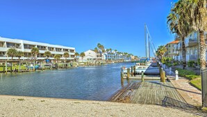 A marina with boats docked, a wooden walkway, and a building with balconies. - Padre Island Retreat on Canal - 2 Mi to Beach! (Corpus Christi)