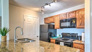 A kitchen with granite countertops, wooden cabinets, stainless steel appliances, and a built-in microwave. - Padre Island Retreat on Canal - 2 Mi to Beach! (Corpus Christi)