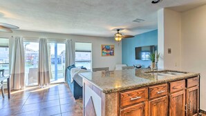 A spacious kitchen with a large island, wooden cabinets, and a ceiling fan. - Padre Island Retreat on Canal - 2 Mi to Beach! (Corpus Christi)