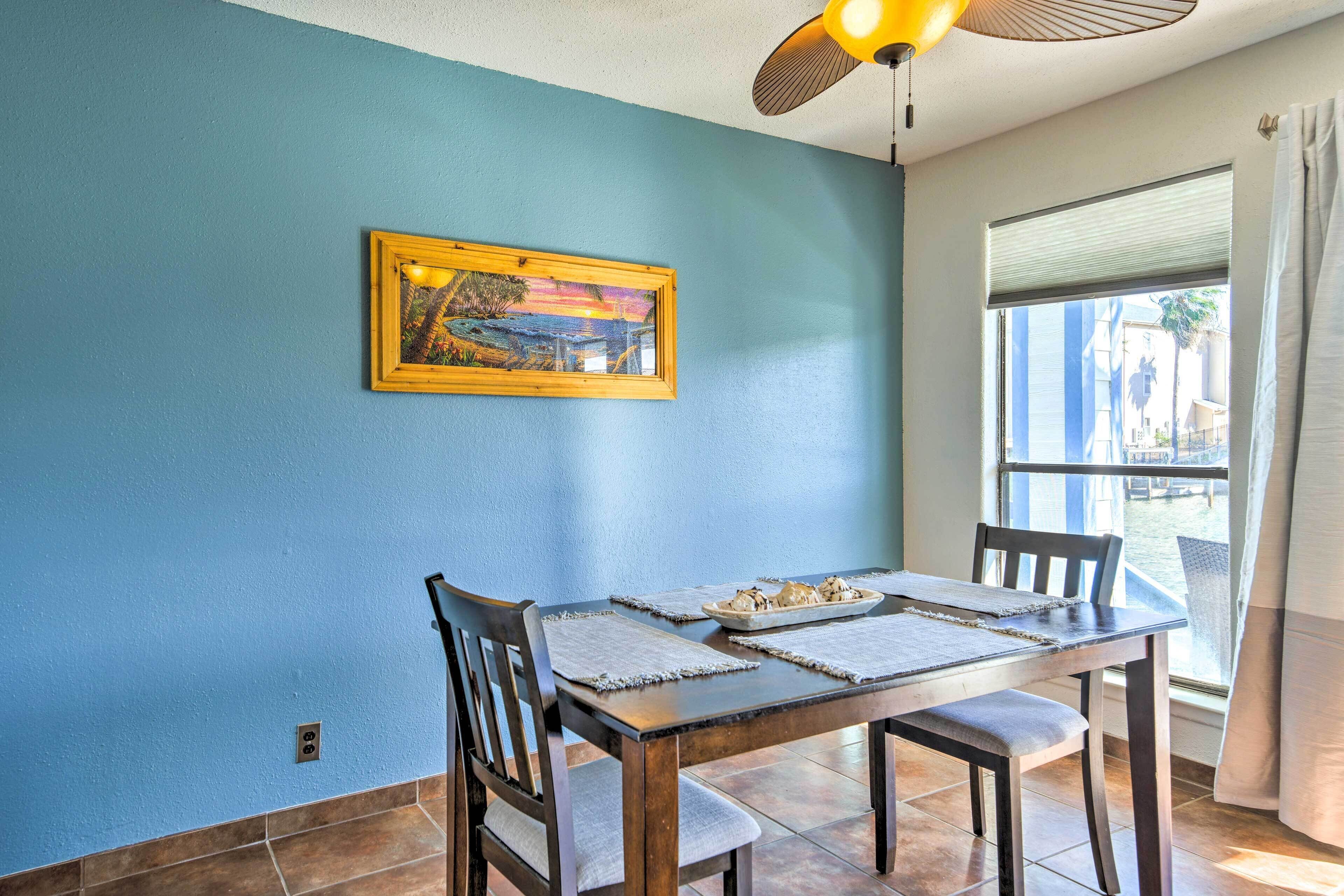 Un comedor con una mesa de madera, dos sillas y una ventana con persianas.