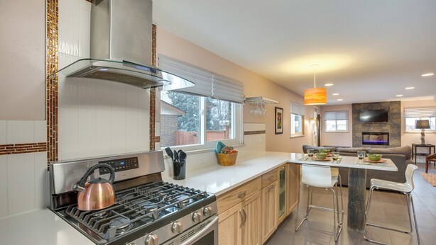 A modern kitchen with stainless steel appliances, a large window, and a dining area with a bar stool. - 9 Mi to Dtwn: Quiet South Denver Apartment (Lakewood)