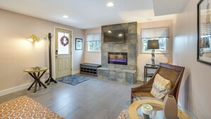 A living room with a fireplace, a comfortable chair, a small table, and a door with a wreath. - 9 Mi to Dtwn: Quiet South Denver Apartment (Lakewood)