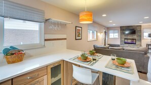 A modern kitchen with a dining area, featuring a built-in oven, a stone fireplace, and a large window with blinds. - 9 Mi to Dtwn: Quiet South Denver Apartment (Lakewood)